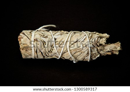 A bundle of dried white sage used for smudging, used by native americans for cleansing and shamanic ceremonies on black background