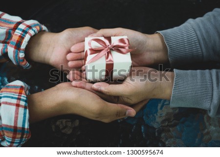 Male gives a gift to female on dark background.happiness moment concepts ideas.Valentine gift