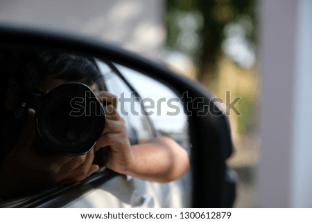 The photographer is pressing the shutter in the car.