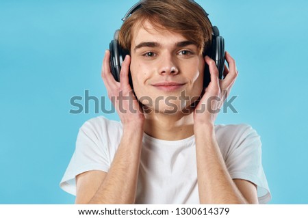 Cute guy in headphones listening to music on a blue isolated background