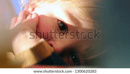 Close-up of handsome toddler blonde boy laying down looking to camera