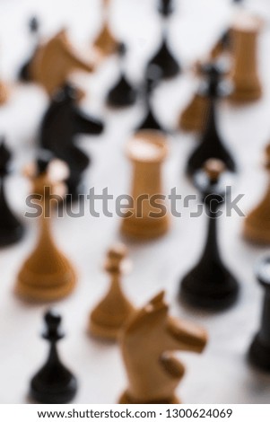 Crowd of black and with chess pieces on a light background. Out of focus. Social concept