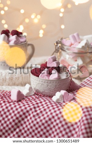 Special delicious breakfast on Saint Valentine day: pink heart shaped marshmallow and fresh raspberry nicely decorated with lights and vintage lamp. Festive mood, holiday inspiration