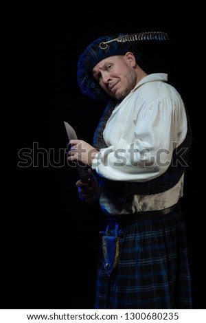 Emotional Man with a beard in a blue checkered Scottish costume posing on a black background