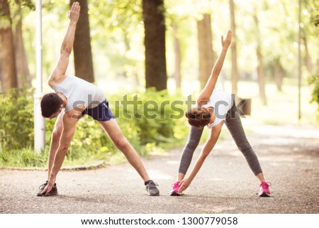 Young couple doing stretching in park