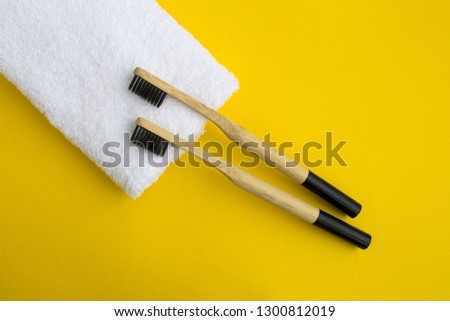 Bamboo toothbrushes and white  towel on the yellow background.Top view.Copy space.