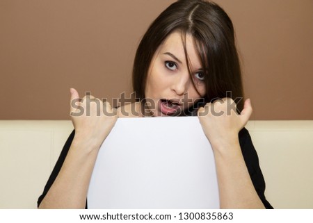 
A young woman with astonishment on her face holding a blank piece of paper.