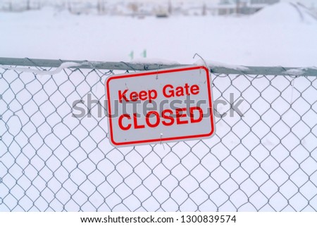 Keep Gate Closed sign on a wire fence against snow