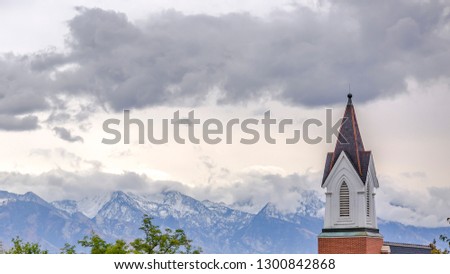 Church steeple against mountain and cloudy sky