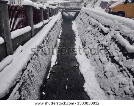 small river landscape with snow in village of Parva, Romania