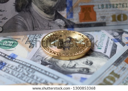 Golden Bitcoins on US dollars. Digital currency close-up. New virtual money. Crypto currency top view. Real coins of bitcoin on banknotes of one hundred dollars. Exchange. Bussiness, commercial.