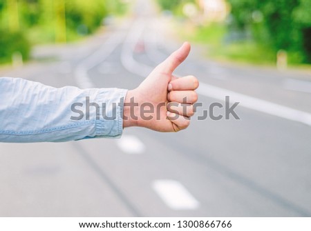 Thumb up gesture try stop car road background. Hand gesture hitchhiking. Make sure you know right gestures to stop car. Thumb up sign not work in many parts of world. Autostop travel. Pick me up.