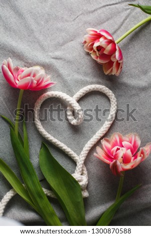 Heart from rope and bouquet of tulips on a gray background with space for text