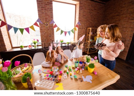 Close up photo three small girls children day wondered taste choco eggs two mommy bring gift glad presents cute table full craft sit big wooden table floor