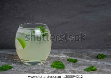 A mojito cocktail in a small oval glass garnished with mint and lime on a rock base and stone background Royalty-Free Stock Photo #1300894312