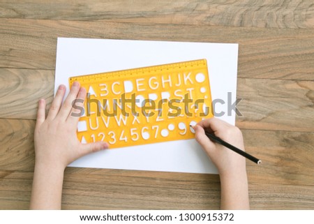 Child alphabet ruler with writes lettering on wood table