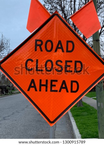 A road closed ahead sign in a residential area.