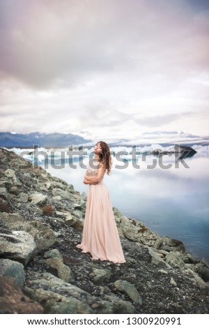 Beautiful young woman is looking at the icebergs of the jokulsarlon glacier lagoon in Iceland