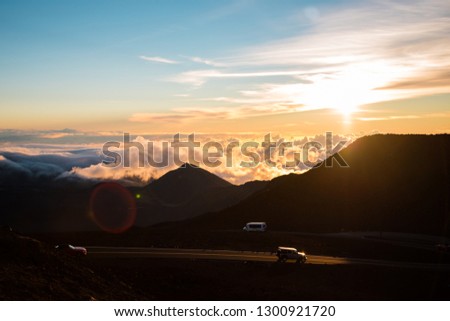 Beautiful Colorful Sunrise Sky at Dusk with Sun Rays Coming Through Clouds from the Top of Haleakala Volcano and Vehicles Driving on Road in Maui Hawaii Amazing Landscape in Island Paradise