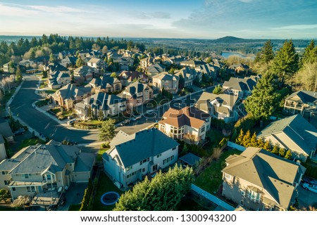 Aerial photo over a high end neighborhood at sunset. A beautiful lake can be seen in the background at the base of a hill.