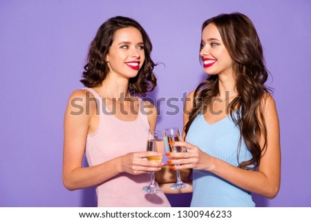 Close up portrait two stunning curly wavy she her ladies in love toast anniversary dating flirty arms hands hold golden beverage wear festive dresses isolated purple violet vivid vibrant background