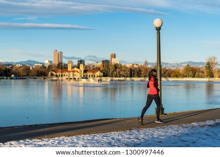 Unrecognizable female runner at Denver's City Park with the city's skyline on the background