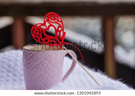 Cup with coffee and red heart on white scarf on balcony background. Good morning Alps, mountains.Mug of fresh morning coffee with Valentine's day card, copy space.pink cup with decorative heart
