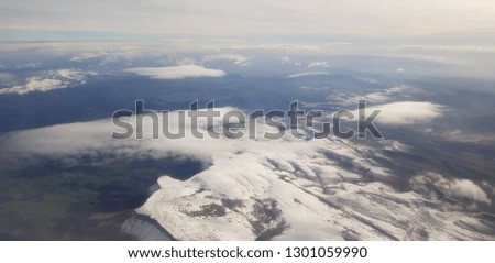 
White clouds over mountains and valleys seen from a plane