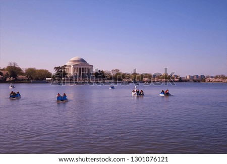 Tidal Basin with paddle boats in the foreground and the Thomas Jefferson Memorial in the background with cherry blossom trees on a clear spring day