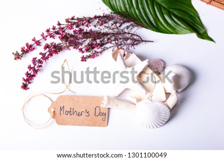A set up of wellness items, a bamboo mat, a shell, candles, a branch, wood, a starfish and a sign saying "Mother's Day"