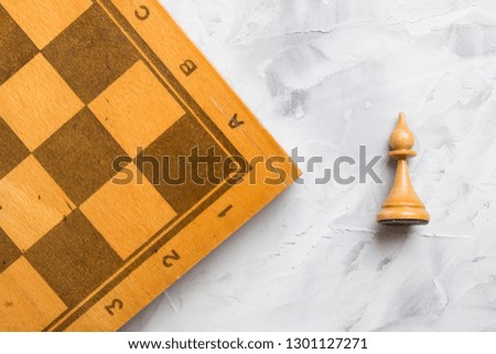 Chess board and  white bishop chess piece lying on a light table
