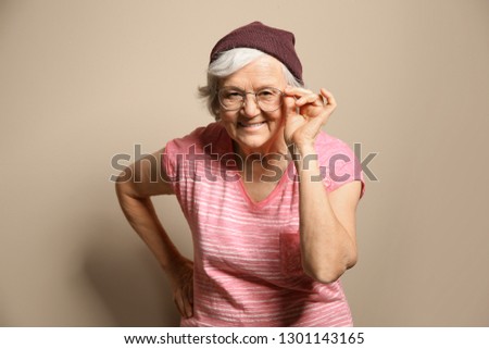 Portrait of elderly woman in hipster outfit on color background