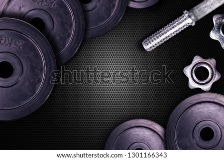 Dumbbells on carbon background. Dumbbells and weights are lying on the floor in the gym. Barbell set and gym equipment. Metal loads in the fitness club.