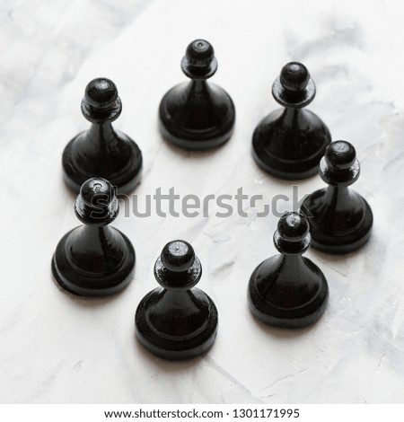 Black pawns chess piece lying on a light table.