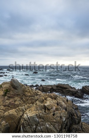 Ocean waves crashing on rocks, coastline view in California. Sand and rocks on a beach