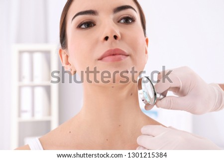 Dermatologist examining patient with magnifying glass in clinic