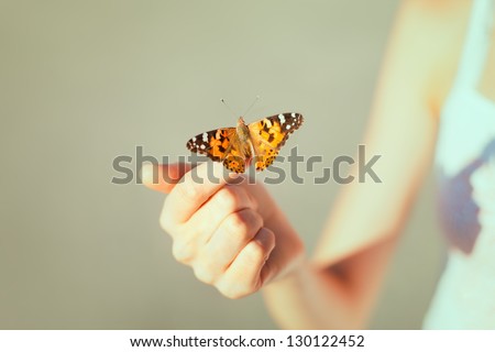 Beautiful butterfly sitting on the girl hand