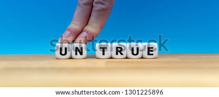 Dice form the word "UNTRUE" while two fingers push the letters "UN" away in order to change the word to "TRUE".