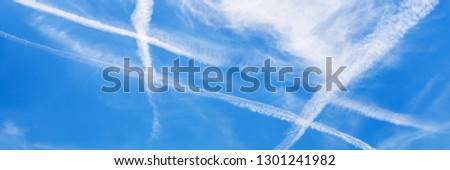 White vapor exhaust from aircraft in blue sky. Weather background with Feathery white clouds in hashtag shape, banner