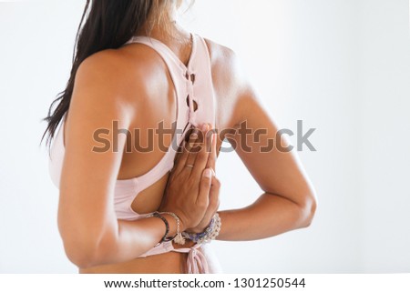 Beautiful slim unidentified brunette crossed her arms behind back during a yoga exercise in cozy home setting against a white wall background. Copyspace