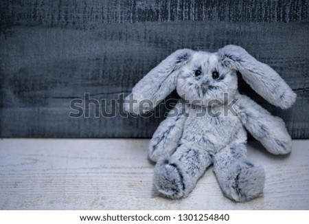 soft toy rabbit made of faux fur on grey wooden background