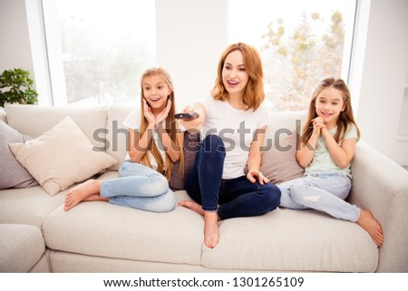 Portrait of nice cute lovely attractive charming cheerful cheery positive sweet blonde people mom mommy mum pre-teen girls sitting on divan watching funny cartoon in house indoors