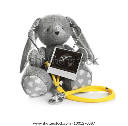 Ultrasound photo of baby and toy rabbit on white background. Concept of pregnancy