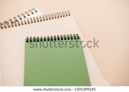 Stationary concept, Flat Lay top view Photo of notepads  on beige background with copy space.Creative flat lay photo of workspace desk with  white and green notebooks minimal style.