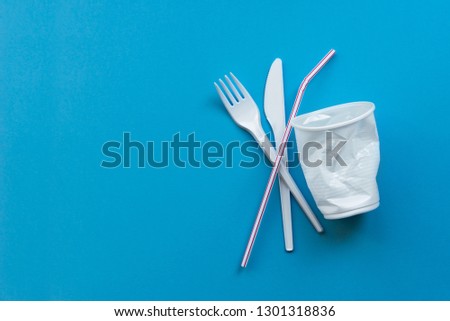 White single-use plastic and plastic drink straws on a blue background. Say no to single use plastic. Environmental, pollution concept. Royalty-Free Stock Photo #1301318836