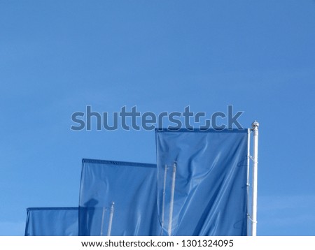 abstract view of waving light blue flags in strong wind on silver color metal poles under blue sky.  For blue sky scenario. blue sky concept. sky is the limit concept.
