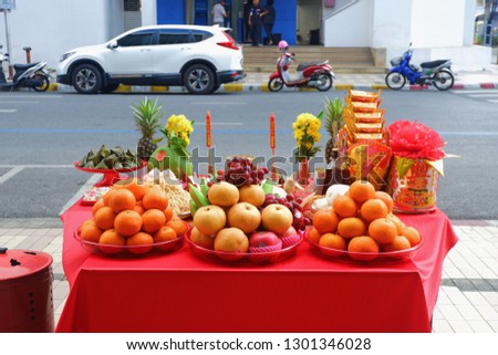 Eye level view on table of apple,orange,pineapple,apple,grape,trolley, dessert, sticky rice cake, flower,food for pay respect to predecessor god Chinese new year festival on the wayside or roadside Royalty-Free Stock Photo #1301346028