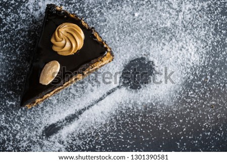 Piece of tasty chocolate cake with condensed milk and poppy, different layers. On a monophonic black background. With almonds and cream. Home-made pastries. Powder.