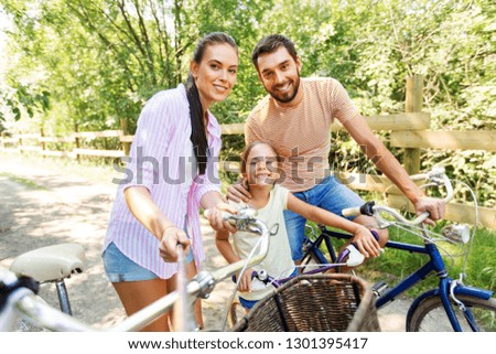family, leisure and people concept - happy mother, father and little daughter with bicycles taking picture by selfie stick in summer park