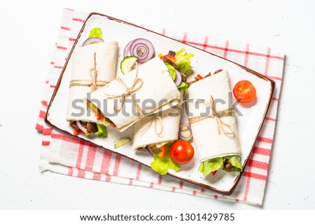 Burritos tortilla wraps with beef and vegetables on white wooden table.  Traditional latin american food. Top view.